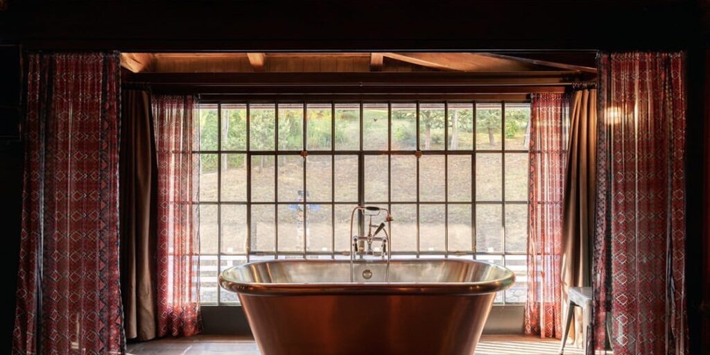 copper roll top bath in a elegant room with a wide window